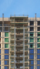 Wall Mural - modern multistory apartment building under construction with scaffolding and hoist frames under a blue sky