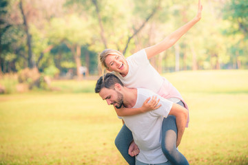 Wall Mural - Portrait image of Young couple enjoying in the park at sunset. Concept romantic and love. Warm tone.