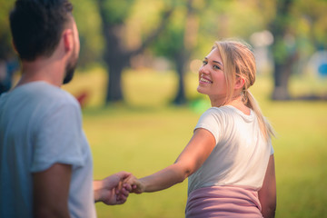 Wall Mural - Portrait image of Young couple enjoying in the park at sunset. Concept romantic and love. Warm tone.