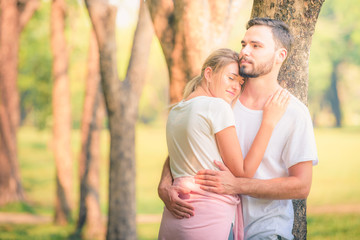 Wall Mural - Portrait image of Young couple enjoying in the park at sunset. Concept romantic and love. Warm tone.