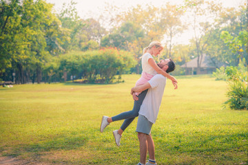 Wall Mural - Portrait image of Young couple enjoying in the park at sunset. Concept romantic and love. Warm tone.