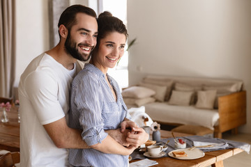 Wall Mural - photo of beautiful brunette couple in love smiling while hugging together in apartment