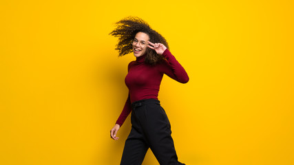 Wall Mural - Dominican woman with curly hair jumping over isolated yellow wall