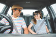 © Nopphon - Front view of Funny moment couple asian man and woman sitting in car. Enjoying travel concept.
