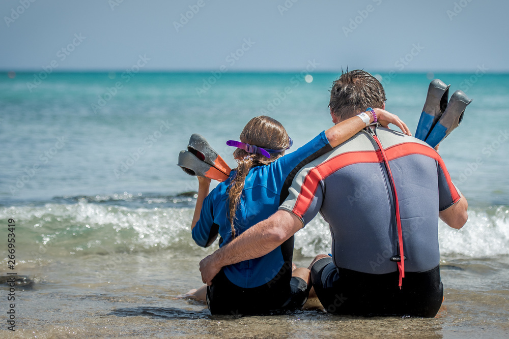 tata z córką odpoczywają na plaży po nurkowaniu w morzu - obrazy, fototapety, plakaty 