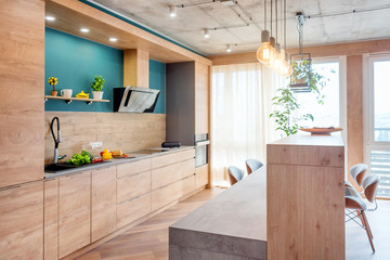 Modern furniture in luxury kitchen. Minimalist scandinavian interior in loft apartment with wooden furniture, lamps, concrete elements and plants