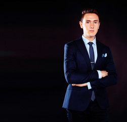 young pretty business man standing on black background, modern hairstyle, talking on phone emotional