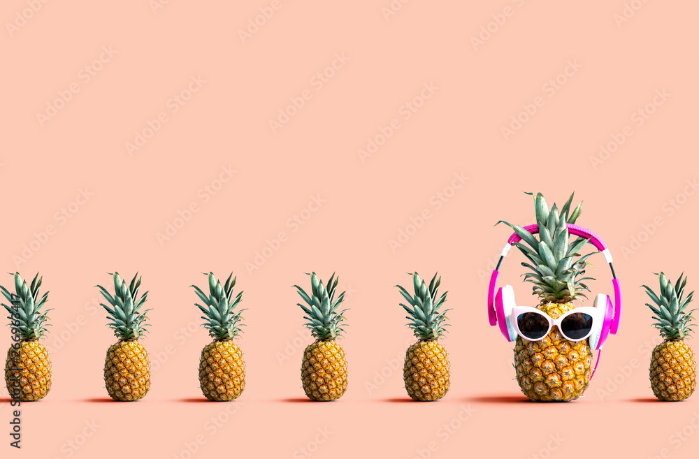 One out unique pineapple wearing headphones on a solid color background - obrazy, fototapety, plakaty 
