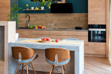 Modern furniture in luxury kitchen. Minimalist scandinavian interior in loft apartment with wooden furniture, lamps, concrete elements and plants