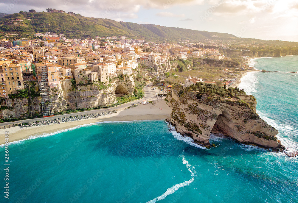 Panorama with beautiful italian town Tropea, in south of Italy with the iconic beach, old town and church at the cliff. Sunset. Drone View - obrazy, fototapety, plakaty 