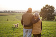 © Westend61 - Back view of happy senior couple standing arm in arm on a meadow enjoying sunset