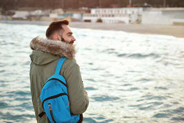 Wall Mural - Stylish young man with backpack near sea