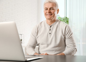 Wall Mural - Mature man using video chat on laptop at home