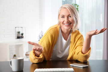 Wall Mural - Mature woman using video chat at home, view from web camera