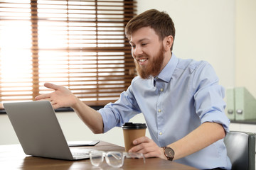 Wall Mural - Man using video chat on laptop in home office