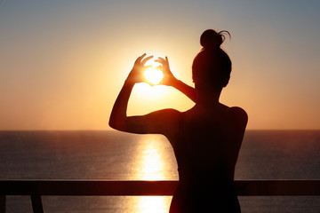 Female Silhouette at the Balcony Making Heart Sign Gesture