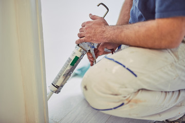 Wall Mural - Worker using silicone for walls and door frame inside the house - renovation fixes.