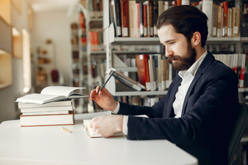 Wall Mural - Man in a library. Guy in a black suit. Student with a books.