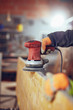 © astrosystem - Carpenter using orbital electric sander in a retro vintage workshop.