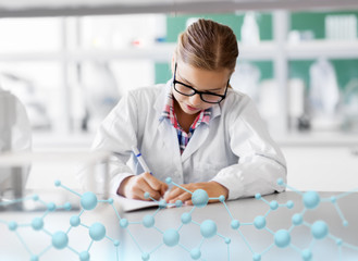 Wall Mural - education, science and children concept - girl studying chemistry at school laboratory and writing to workbook