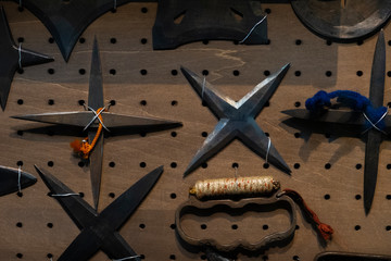 Closeup of collection of authentic and original rusty vintage Japanese Shuriken Ninja Throwing Stars and Knuckle Duster attached to wall