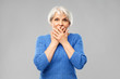 © Syda Productions - emotion, expression and old people concept - portrait of confused senior woman in blue sweater covering her mouth by hands over grey background