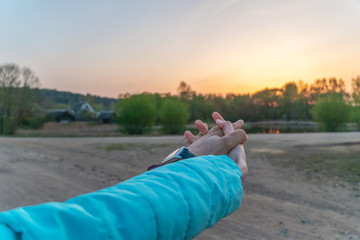 Wall Mural - Romantic couple holding hands and watching the beautiful sunset. Man and woman hold hands, arms stretched forward