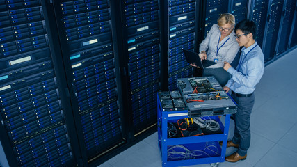 Aufkleber - In the Modern Data Center: Engineer and IT Specialist Work with Server Racks, on a Pushcart Equipment for Installing New Hardware. Specialists Doing Maintenance and Diagnostics of the Database.