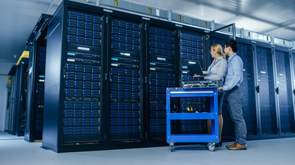 Aufkleber - In the Modern Data Center: Engineer and IT Specialist Work with Server Racks, on a Pushcart Equipment for Installing New Hardware. Specialists Doing Maintenance of the Database. Low Angle Shot.