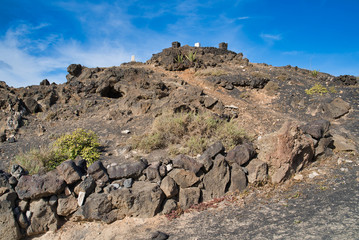 Wall Mural - Hill made of lava stones on promenade of Playa grande with path leading to the mirador in Puerto del Carmen, Lanzarote, Spain