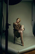© EkaterinaJurkova - beautiful light-skinned and fair-haired girl in a beige coat is sitting in the studio on a chair.