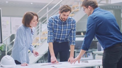 Leinwandbilder - In the Industrial Engineering Facility: Female Designer Works with Industrial Engineer and Master Technician, They have Discussion, Analyse Engine Design Technical Drafts that are Lying on the Table