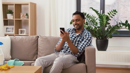 Sticker - household and technology concept - happy indian man using smartphone after cleaning home