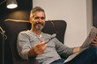 © cherryandbees - middle aged man reading newspaper relaxed in his sofa at home