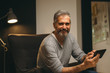 © cherryandbees - portrait of bearded middle aged man using cellphone relaxed in sofa at his home