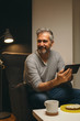© cherryandbees - portrait of bearded middle aged man using tablet relaxed in sofa at his home