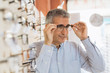 © cherryandbees - middle aged man choosing eye glasses in optic store