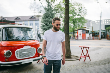 Sticker - Handsome hipster man in sunglasses walking along the street. White t-shirt.