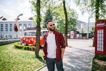 Poster - Handsome hipster man in sunglasses walking along the street. White t-shirt.