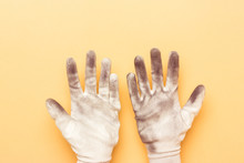 Hands In Dirty Gloves On Yellow Paper Background