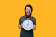 © Vulp - Excitd bearded guy with galsses, holding a clock, standing over yellow background