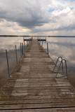 Fototapeta Pomosty - A small bridge over the lake. Reflection of clouds on the lake's surface.