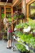 © ML Harris - Happy, smiling middle-aged woman customer shopping for flowers plants at a garden center shop store