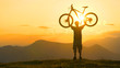 © helivideo - COPY SPACE: Bicycle rider celebrates finishing long cross country trip at sunset