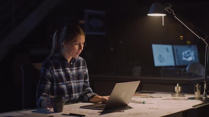 Beautiful Female Engineer Sitting at Her Desk Works on a Laptop Computer