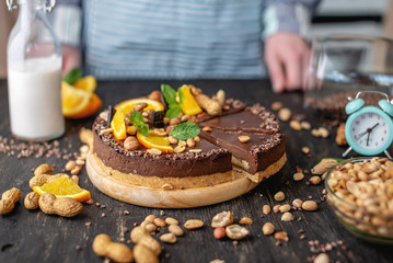 Hands decorated with chocolate cake orange and peanuts and nuts. Concept healthy raw desserts for vegan food