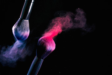 Splash of powder on a black background brushes for make up on a black background.