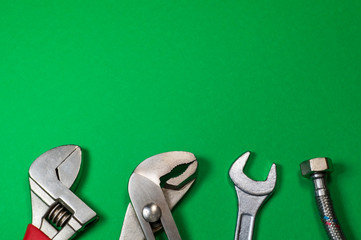 Necessary set of tools for plumbers on a green background.