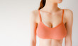 © yayha - Woman is Breast in Orange Underwear Posing on Grey Background,Show Bra. Cropped Close Up of Sexy Female Wearing Sport Bra (Sportswear) with Perfect Chest. Fitness and Yoga Healthy Lifestyle Concept.