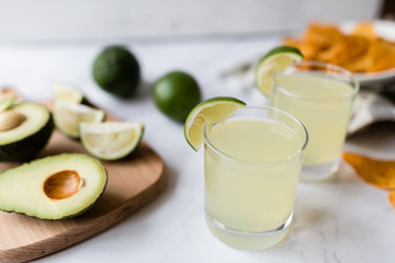 Wall Mural - Fresh avocado, lime, drink and nacho chips lying on marble background. Recipe for Cinco de Mayo party